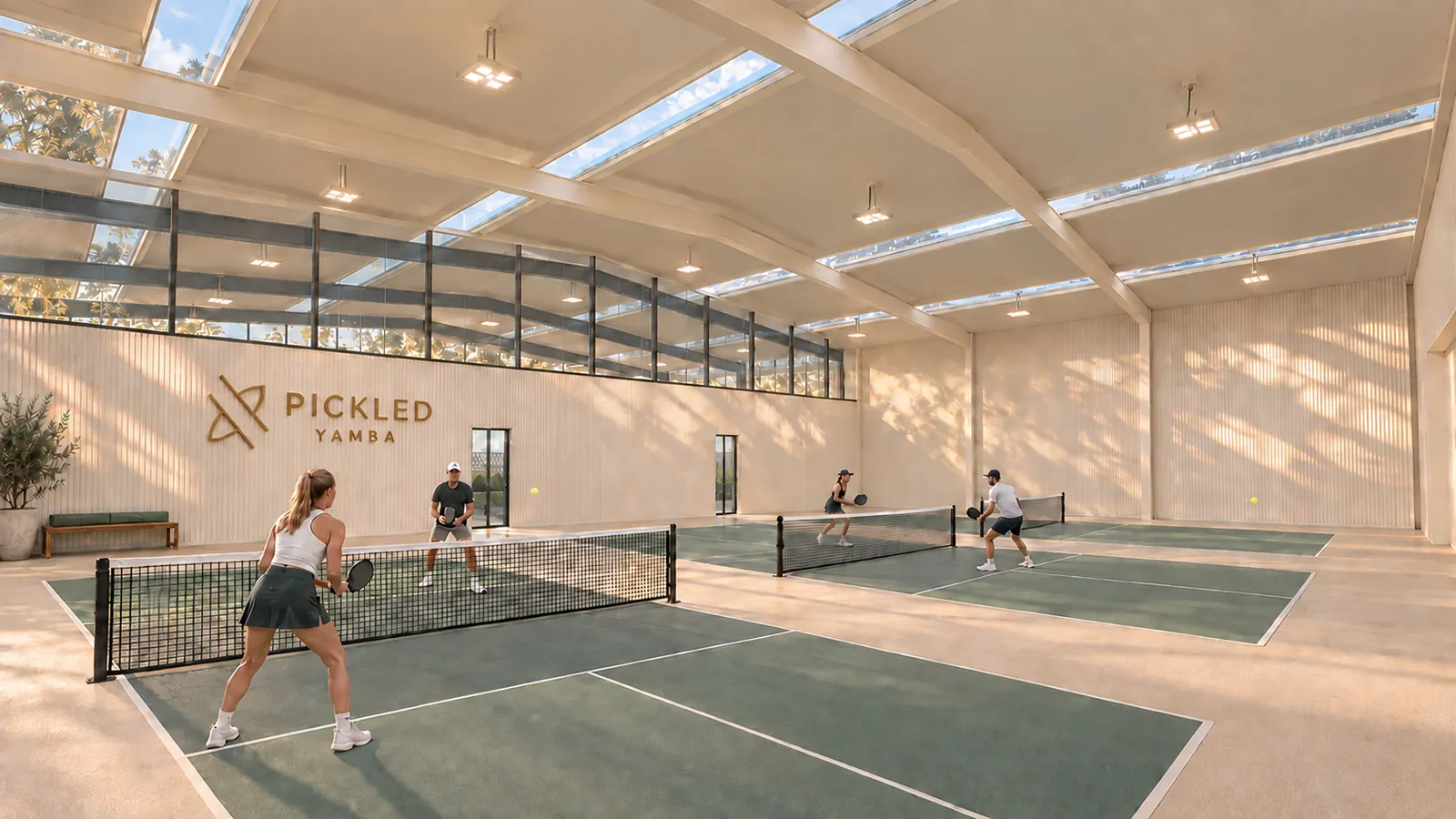 Doubles on sage-green courts inside the hall, high windows and steel frames overhead